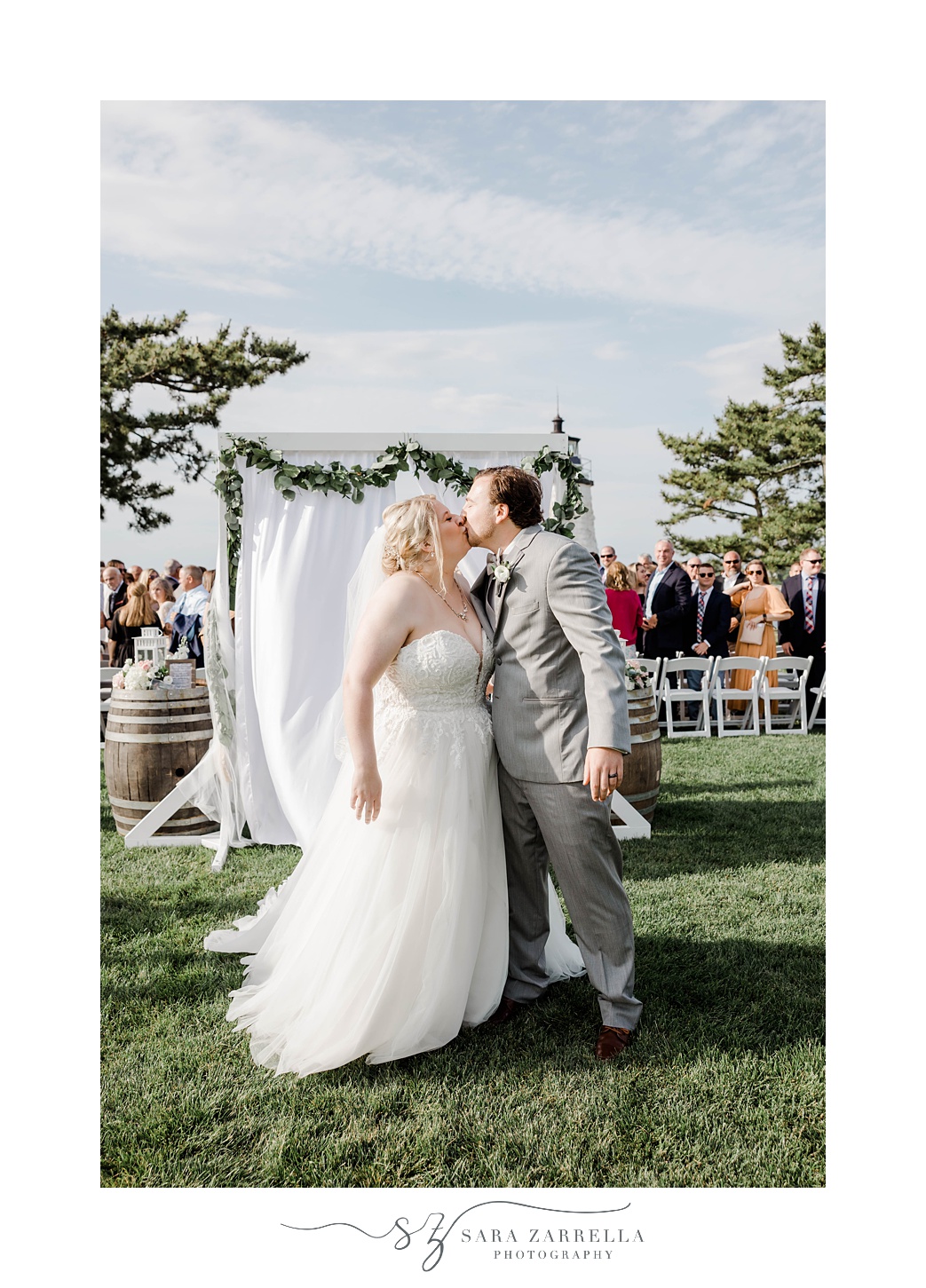 bride and groom kiss at the end of the aisle at Gurney’s Newport