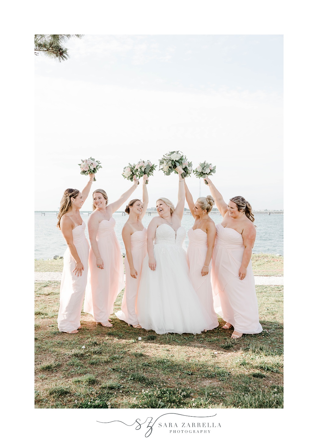 bride cheers with bridesmaids during portraits in Rhode Island