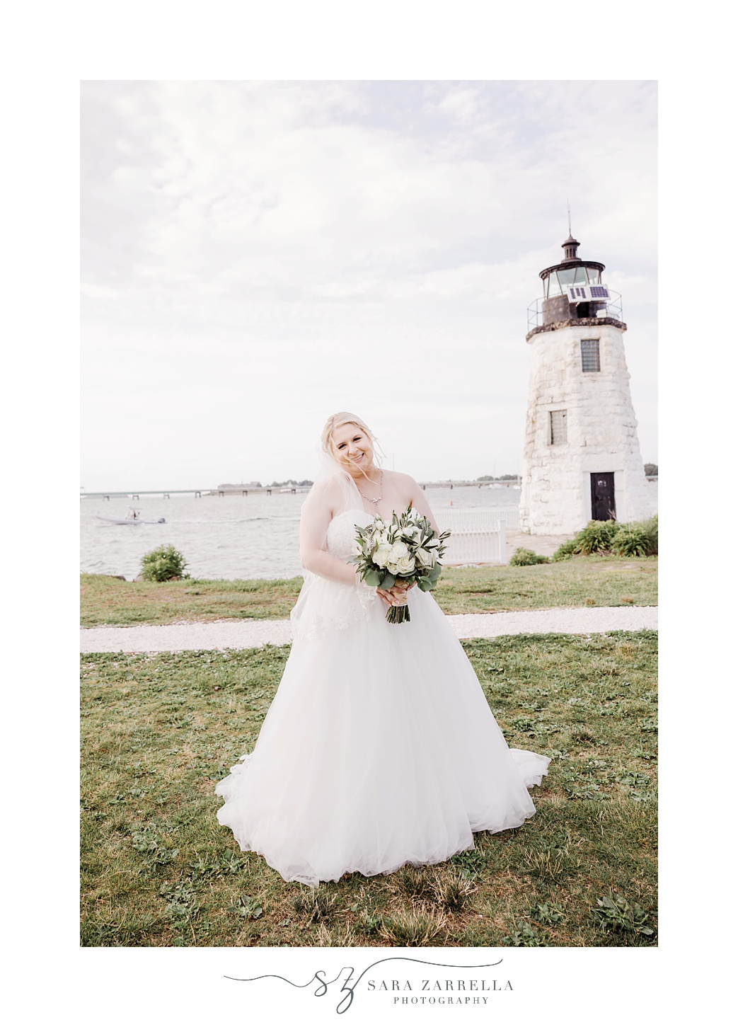 bride stands by lighthouse at Gurney’s Newport