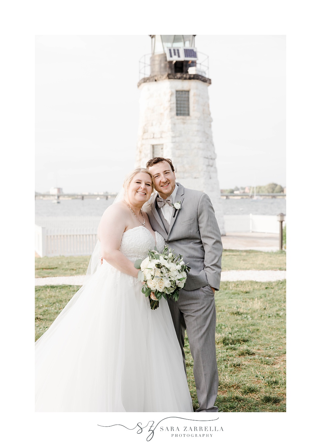 bride and groom hug by lighthouse at Gurney’s Newport