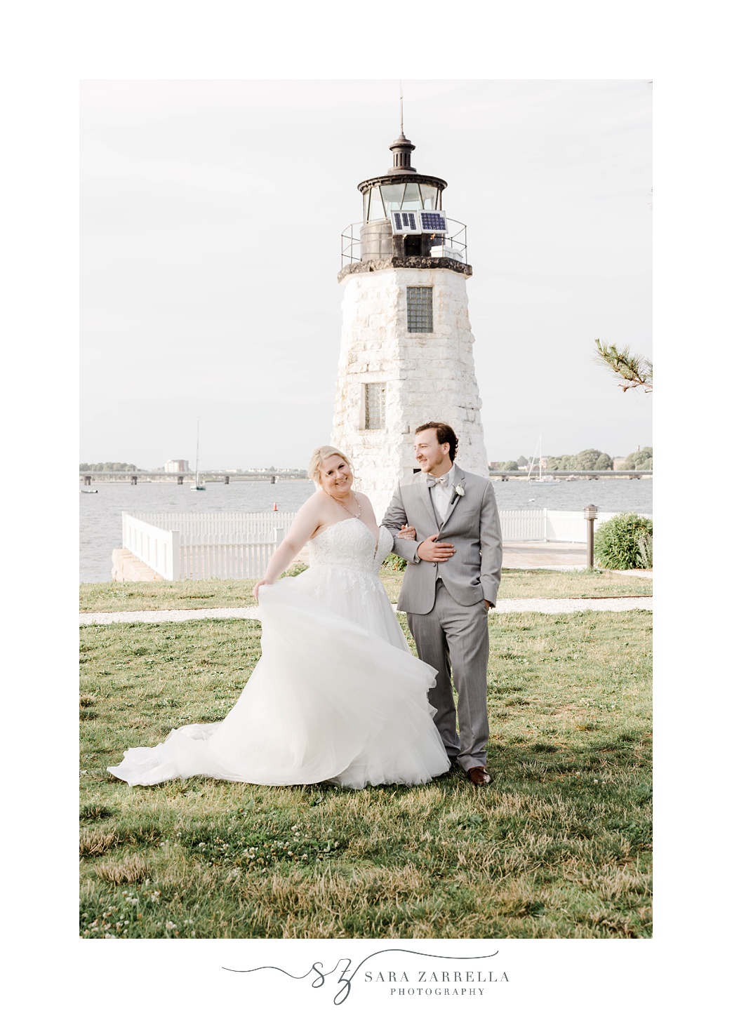 bride twirls wedding dress with groom near lighthouse 