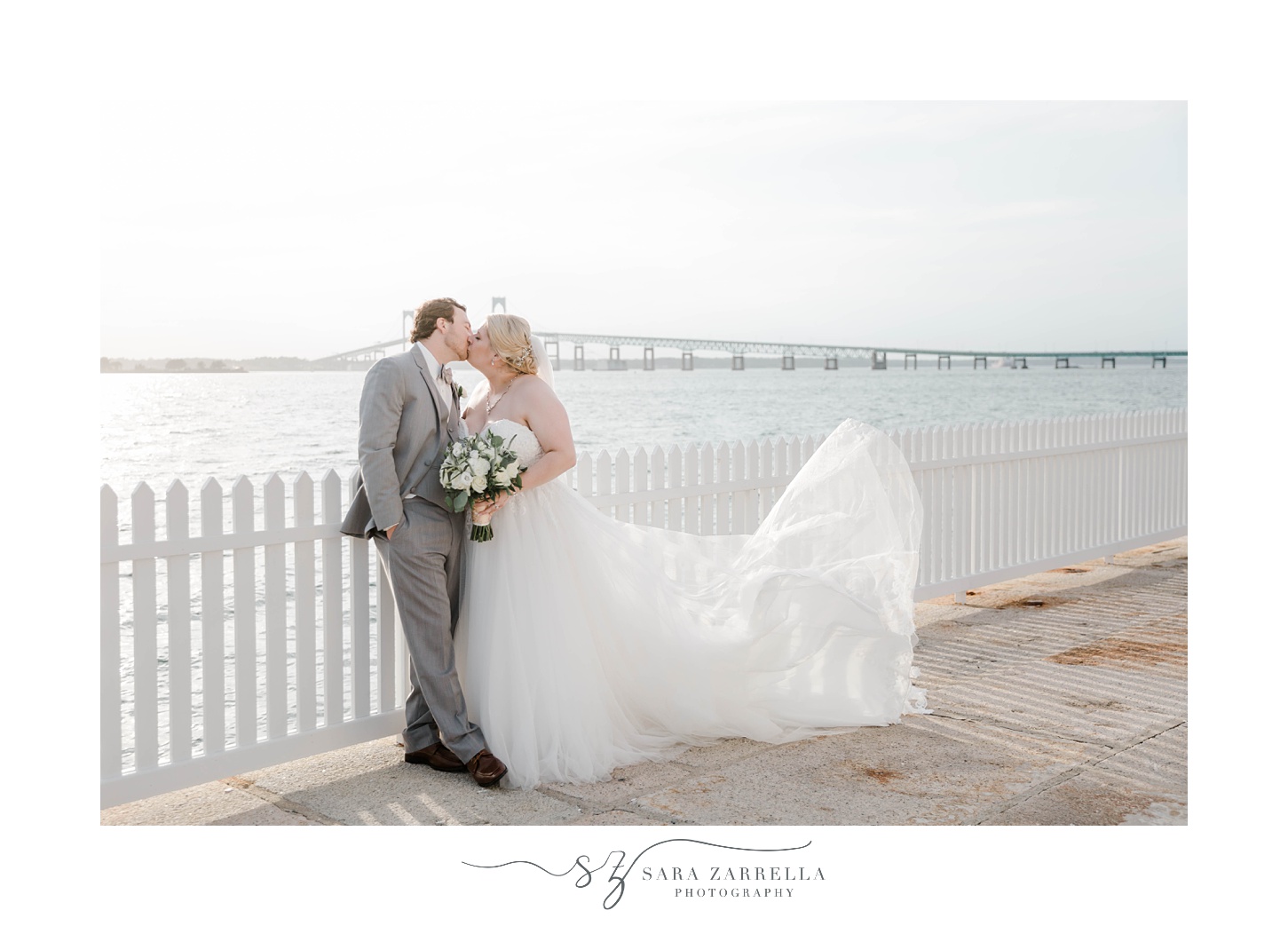 newlyweds kiss by white fence in Newport RI