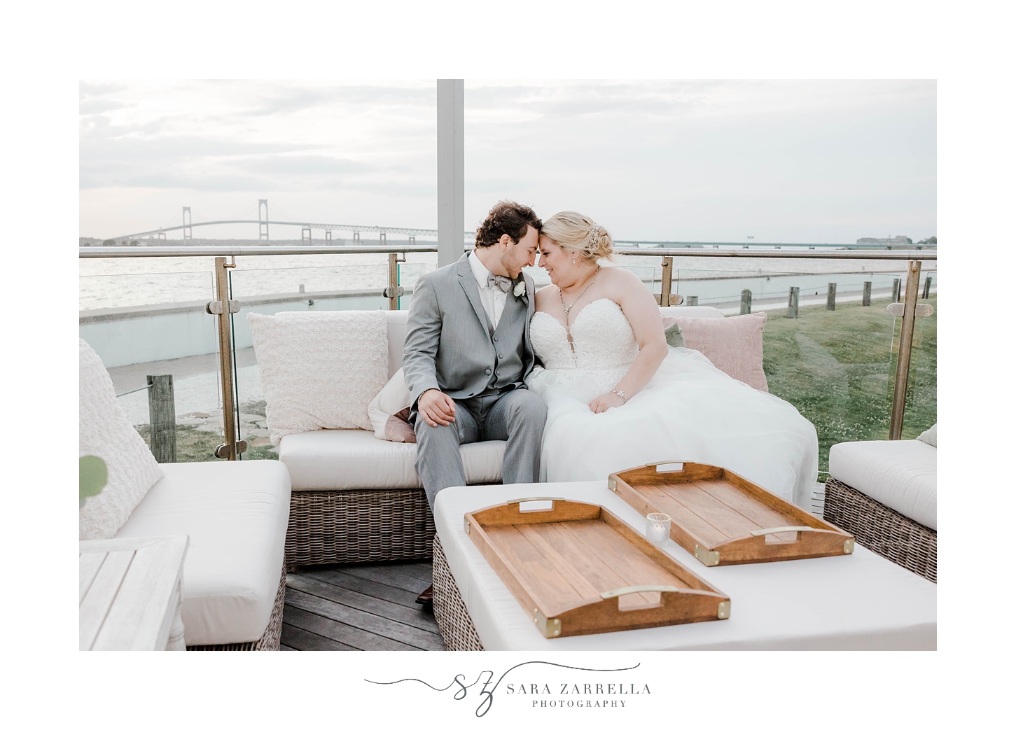 newlyweds sit on couch on deck at Gurney’s Newport