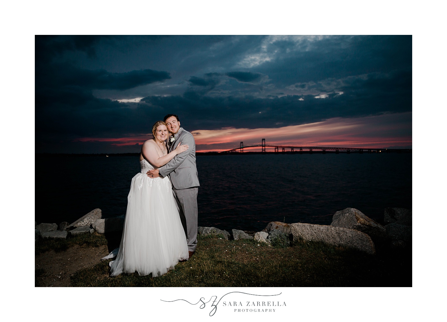 bride and groom hug on rocks in Newport RI at sunset
