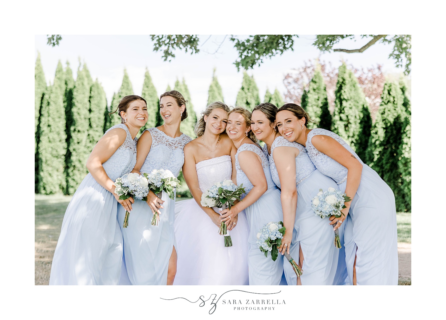 bride poses with bridesmaids in light blue gowns at Harbor Lights