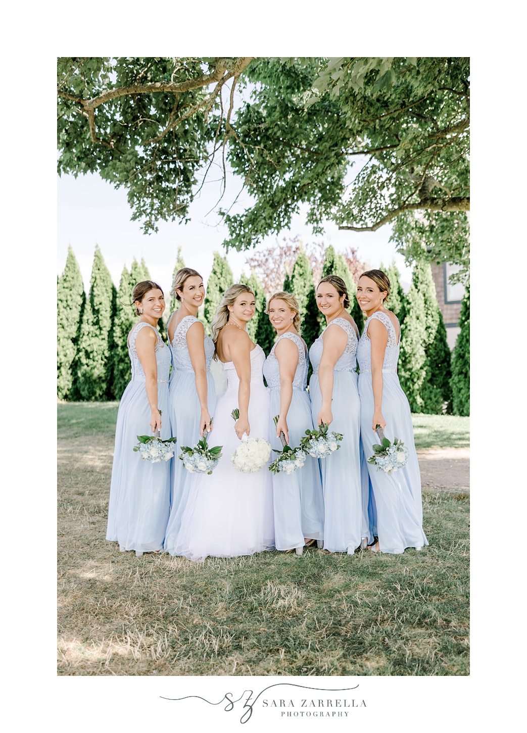 bride stands with bridesmaids in light blue gowns at Harbor Lights