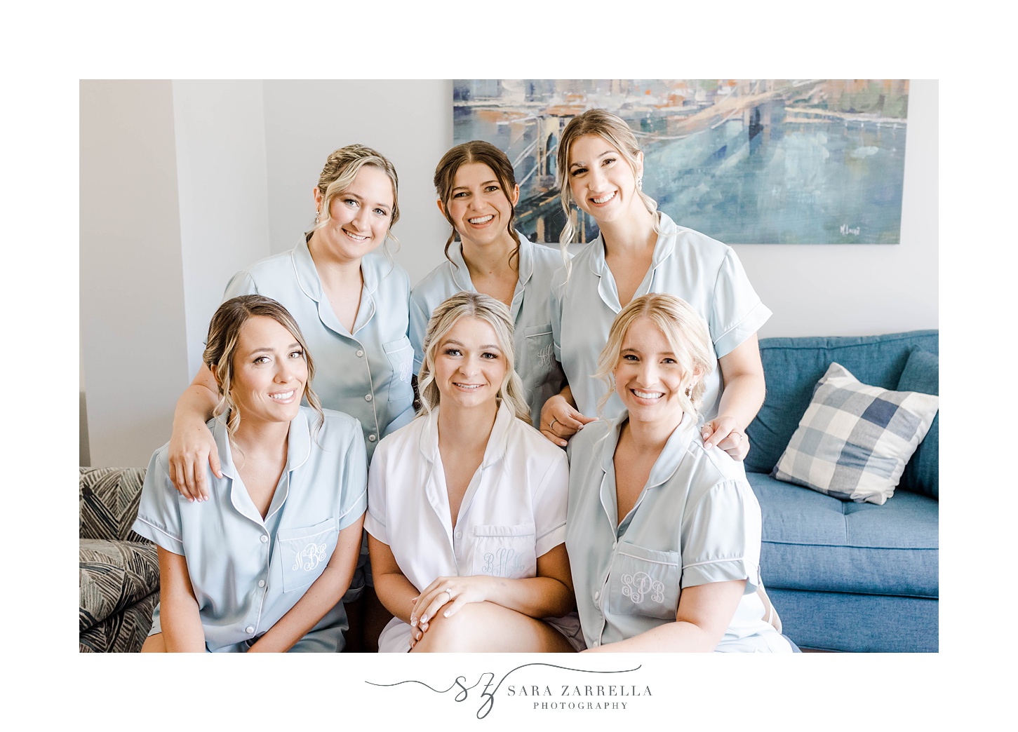 bride sits with bridesmaids in blue pjs in bridal suite