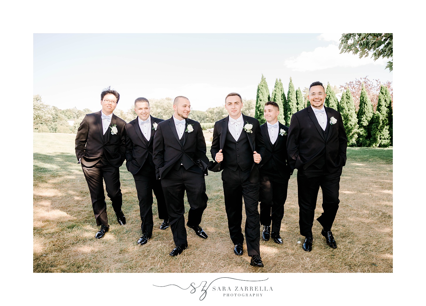 groom walks with groomsmen in black suits with white ties