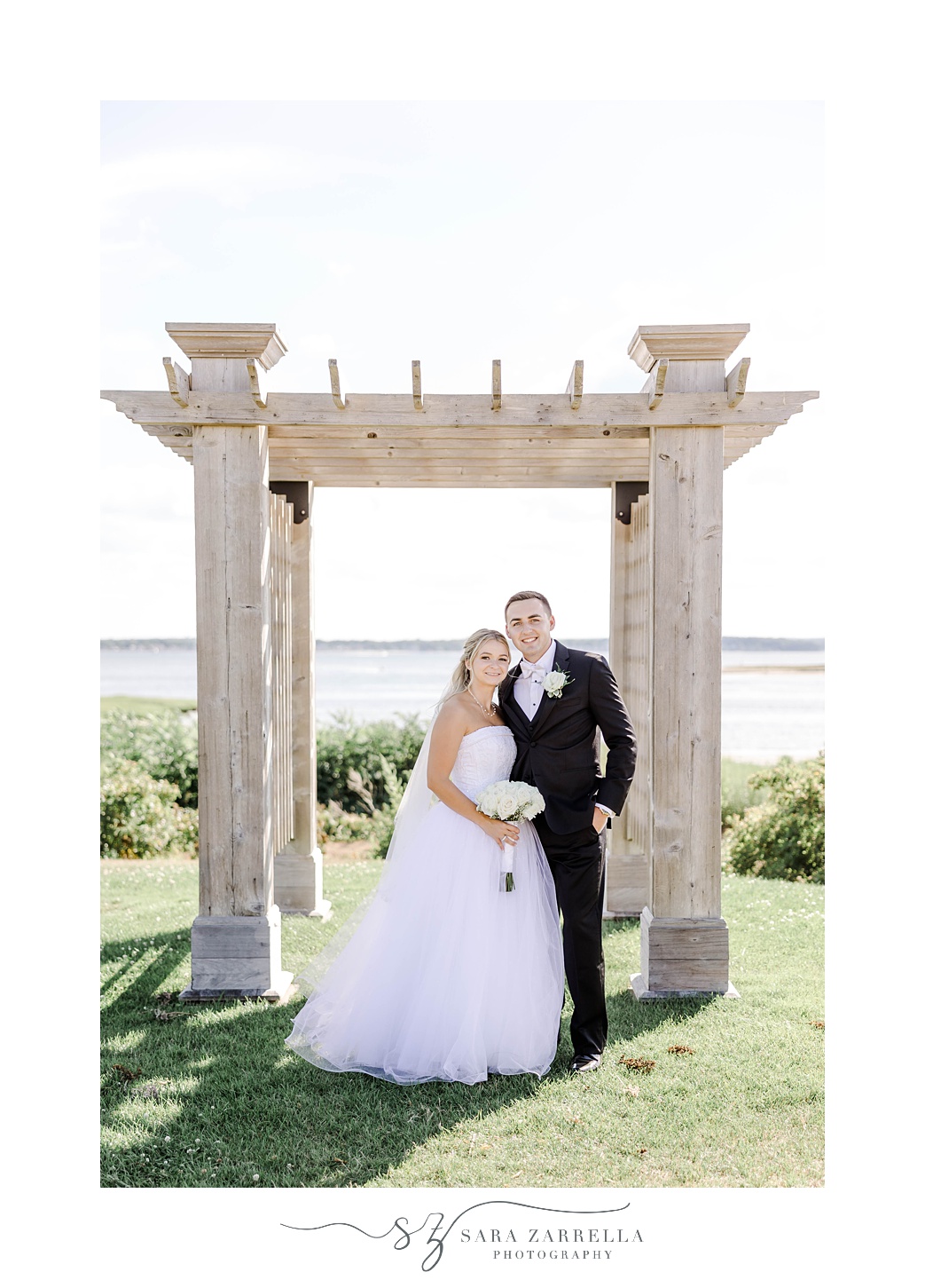 newlyweds pose by stone arbor at Harbor Lights