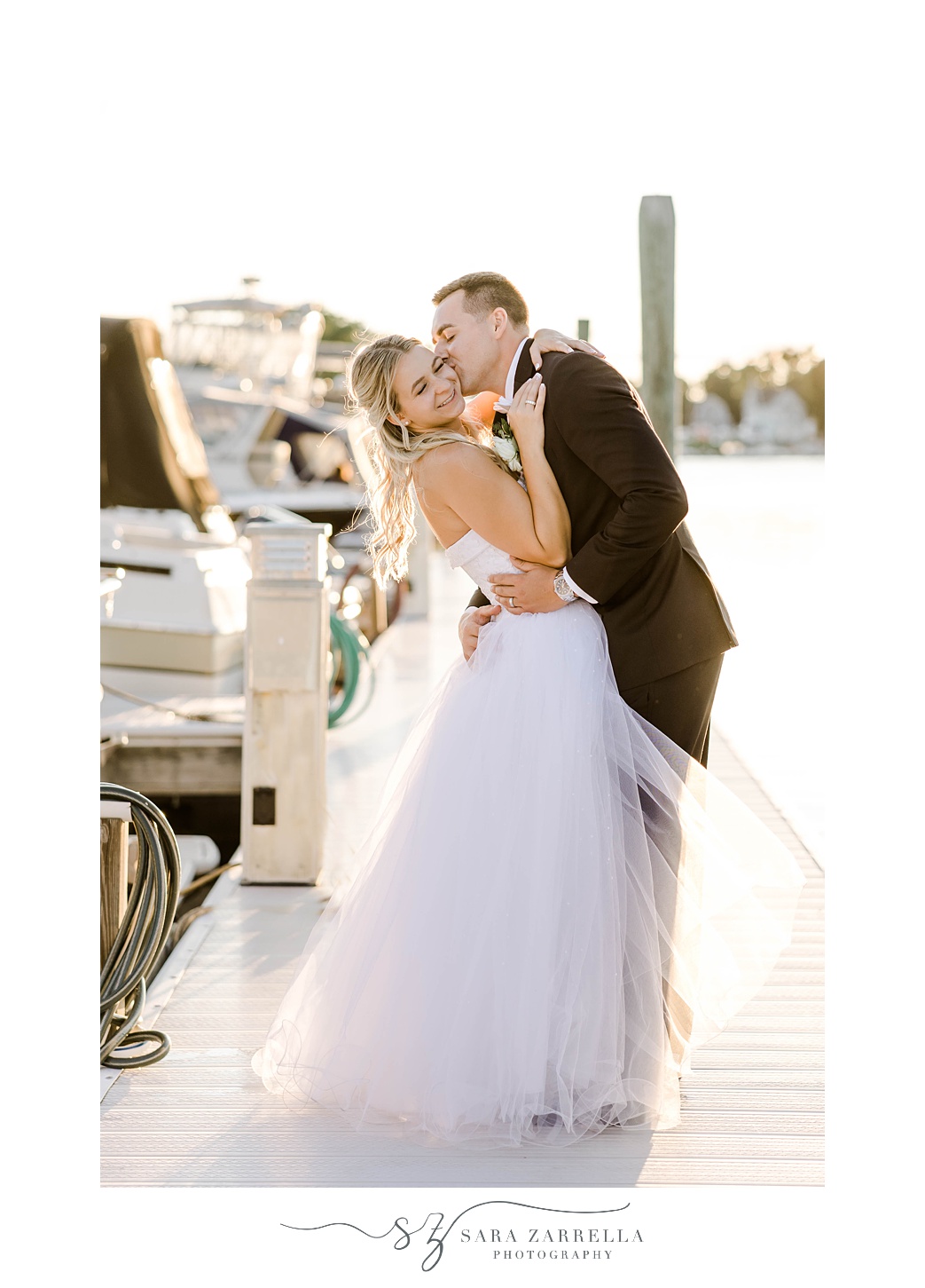 sunset portrait of groom kissing bride's cheek on dock