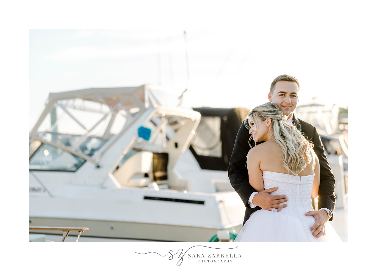 newlyweds hug in front of marina at Harbor Lights