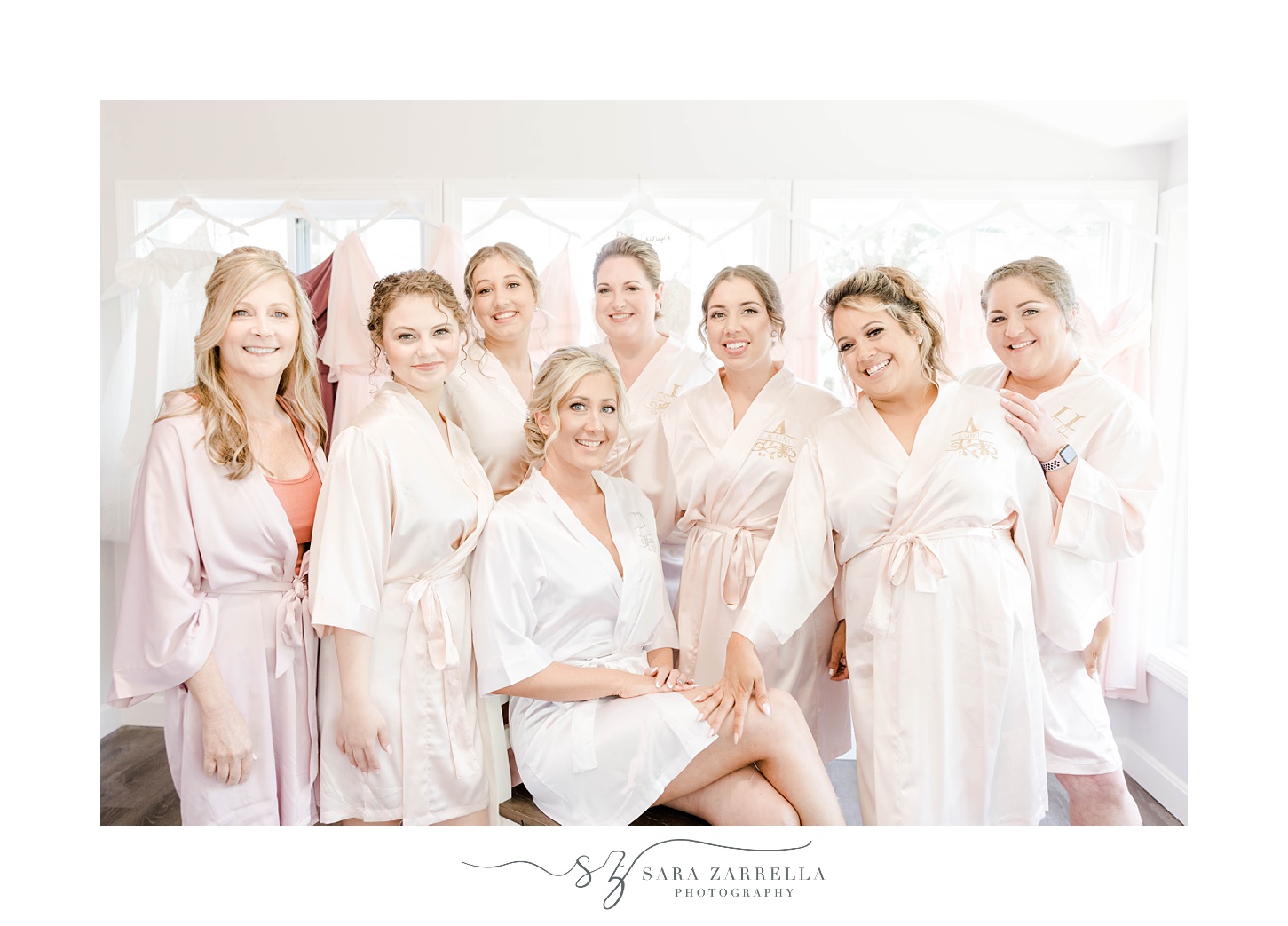 bride sits with bridesmaids in matching pale pink robes