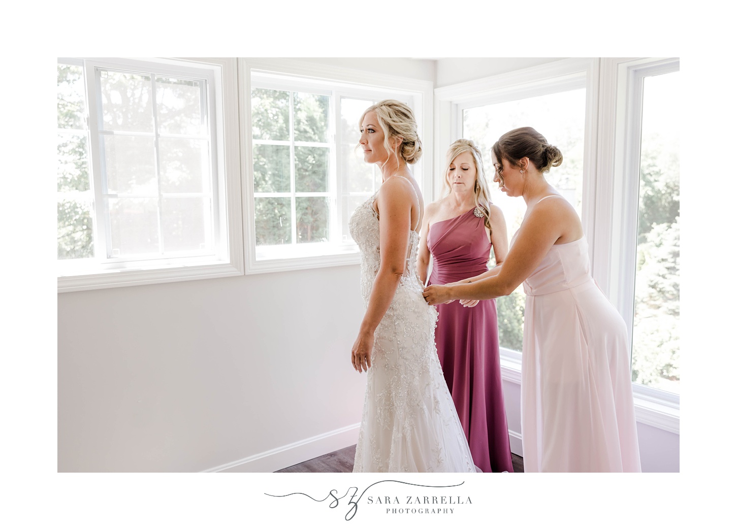 bridesmaid and mother help bride into gown for Warwick RI wedding 
