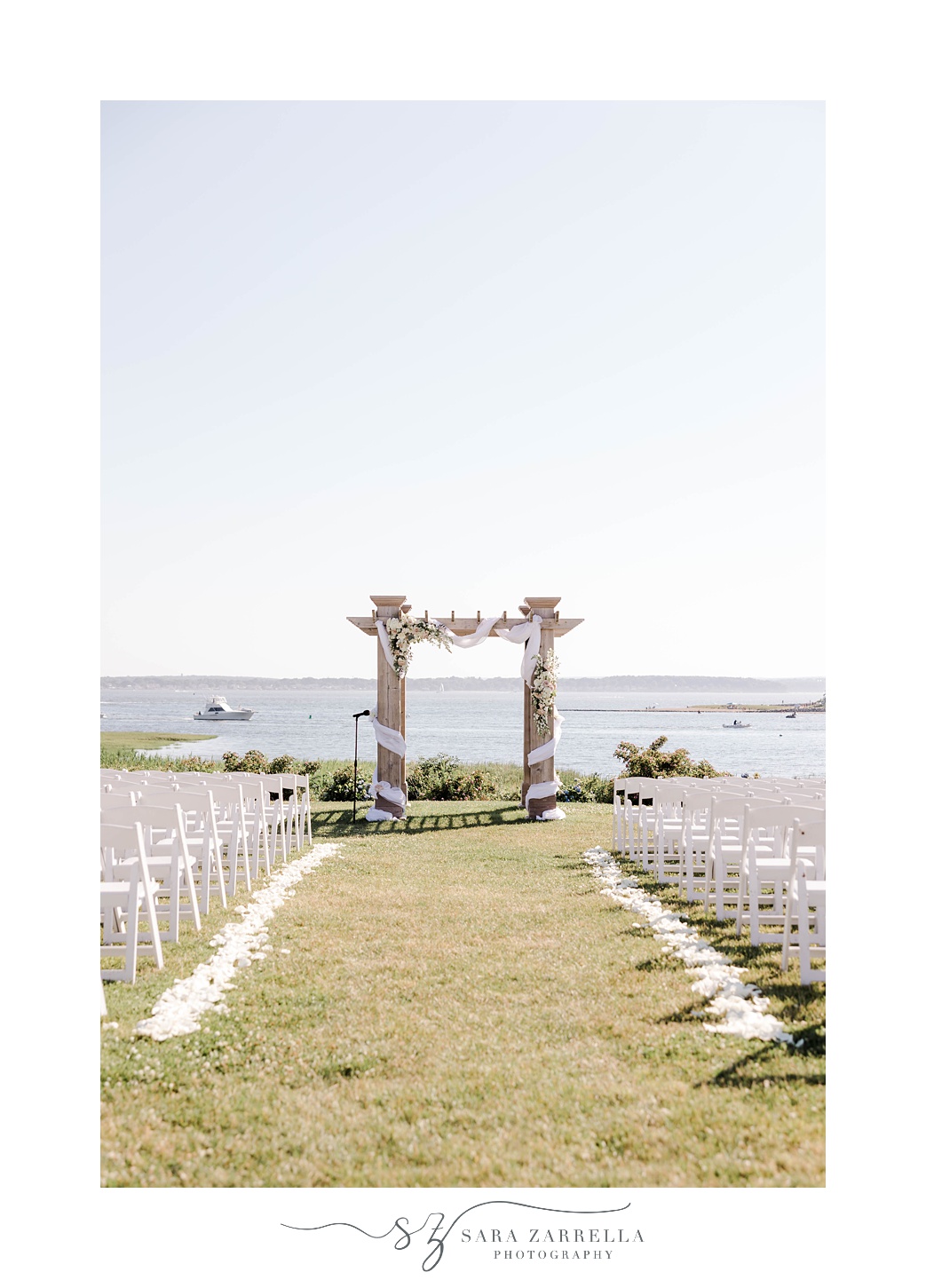 ceremony arbor draped in white fabric and flowers at Harbor Lights