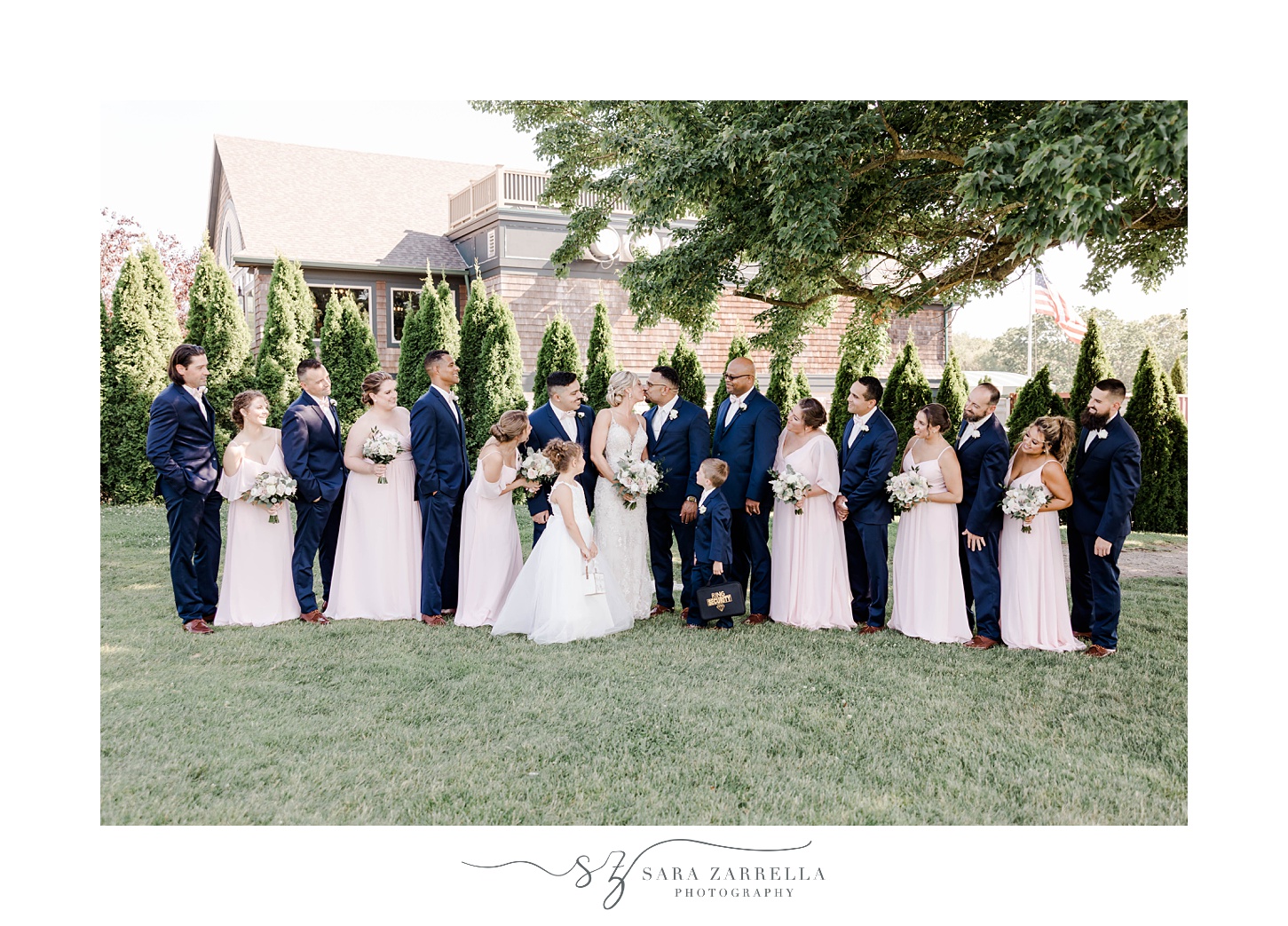 bride and groom stand together with wedding party in navy and pink attire