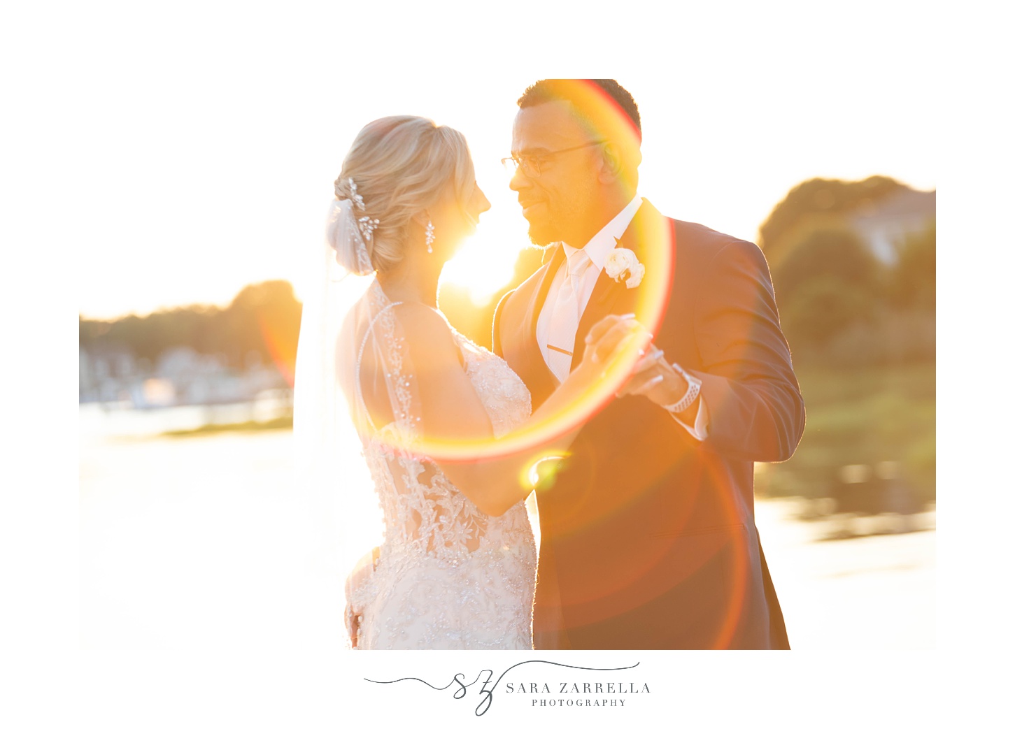 couple smiles together with sun flare around them during portraits at Harbor Lights