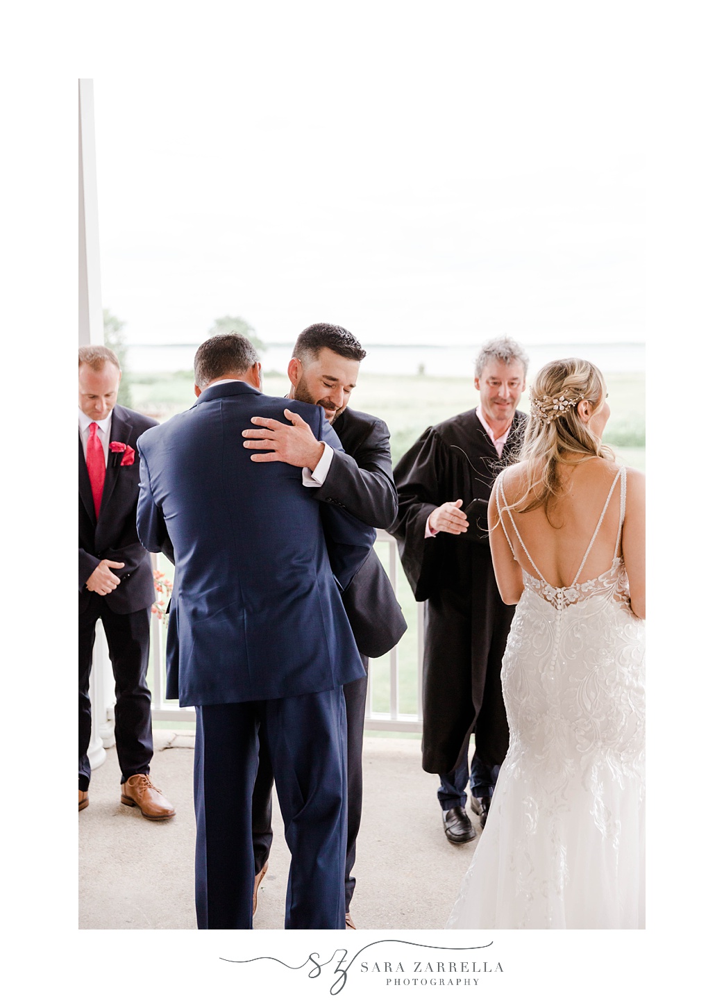 groom shakes hands and hugs bride's dad during ceremony in Rhode Island