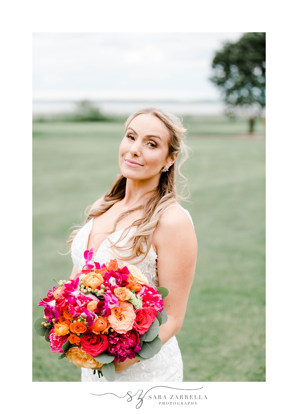 bride smirks holding bright bouquet of pink and orange flowers