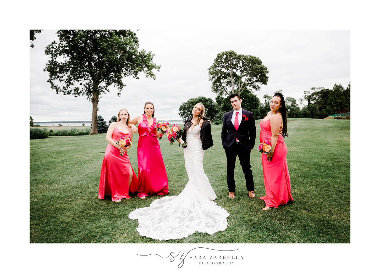 bride stands with bridesmaids in pink gowns and groomsman in black suit at Quidnessett Country Club