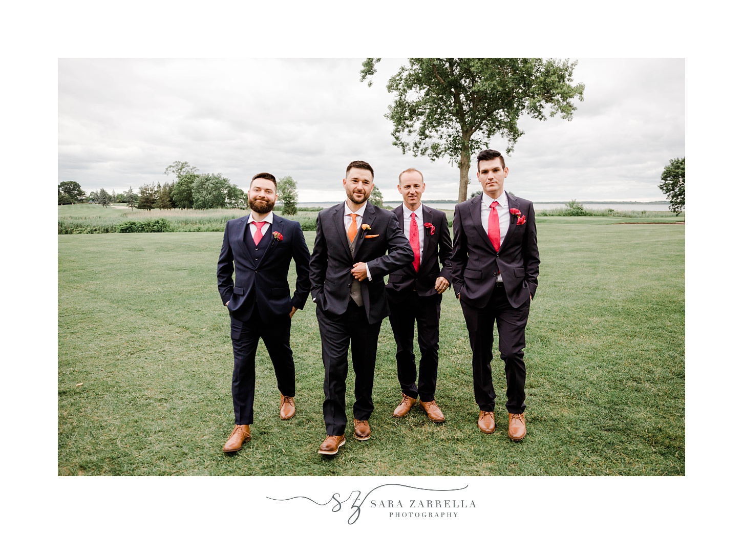 groom walks with groomsmen in black suits at Quidnessett Country Club