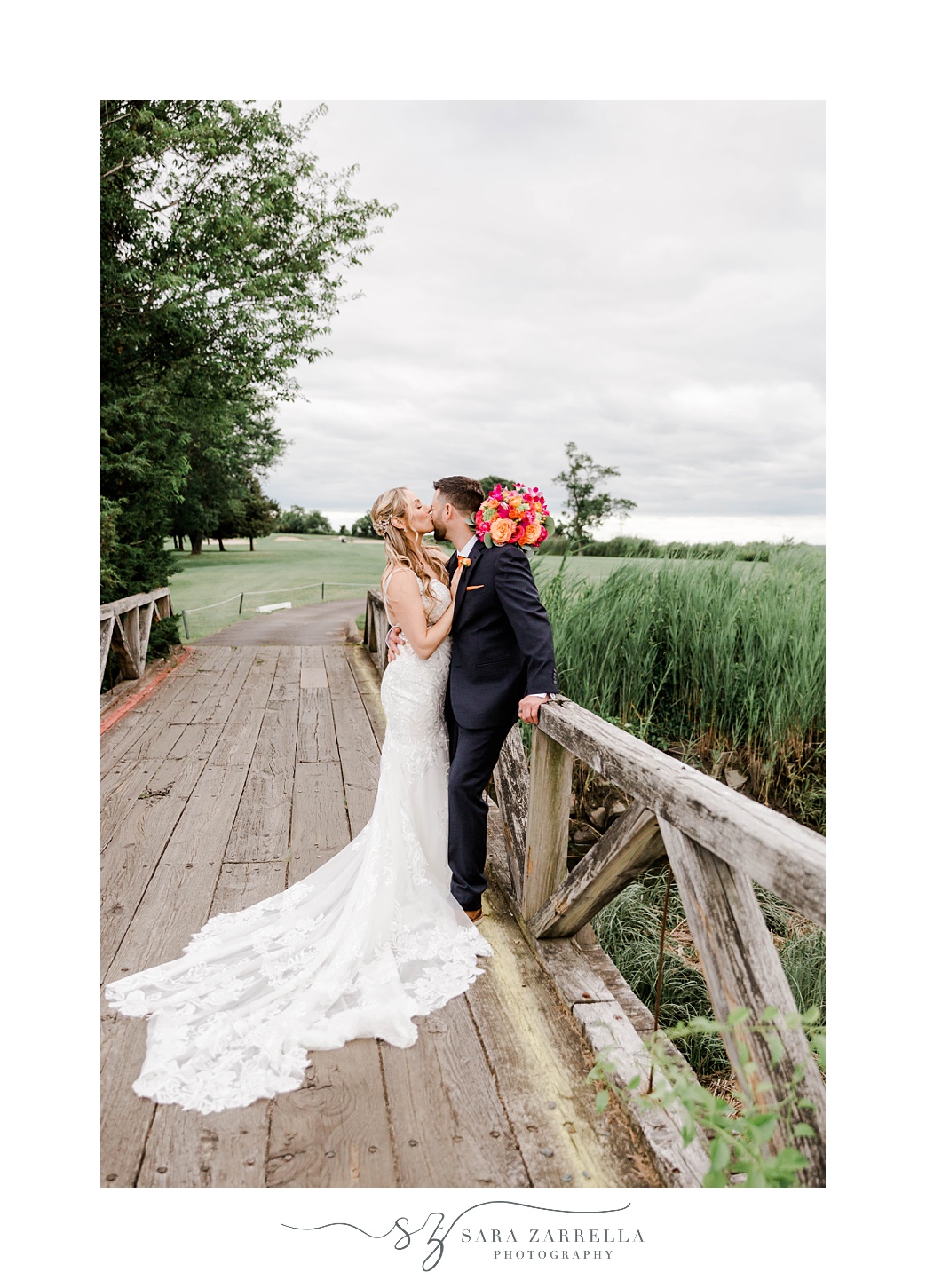 newlyweds kiss on wooden bridge at Quidnessett Country Club