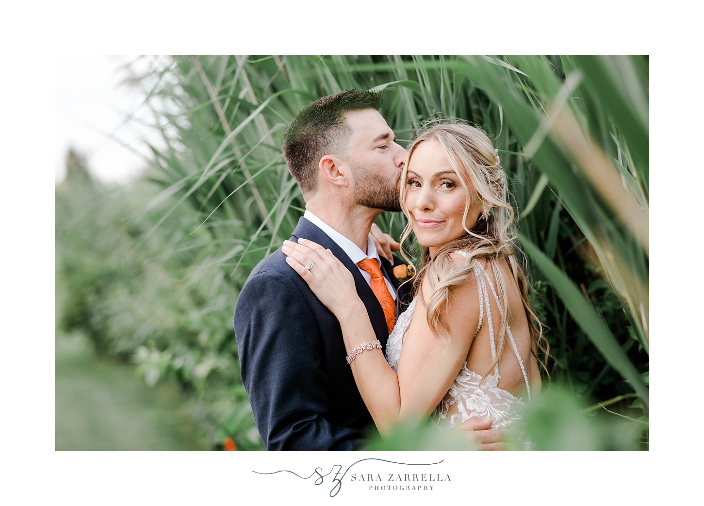 groom kisses bride's forehead during RI wedding portraits in grass