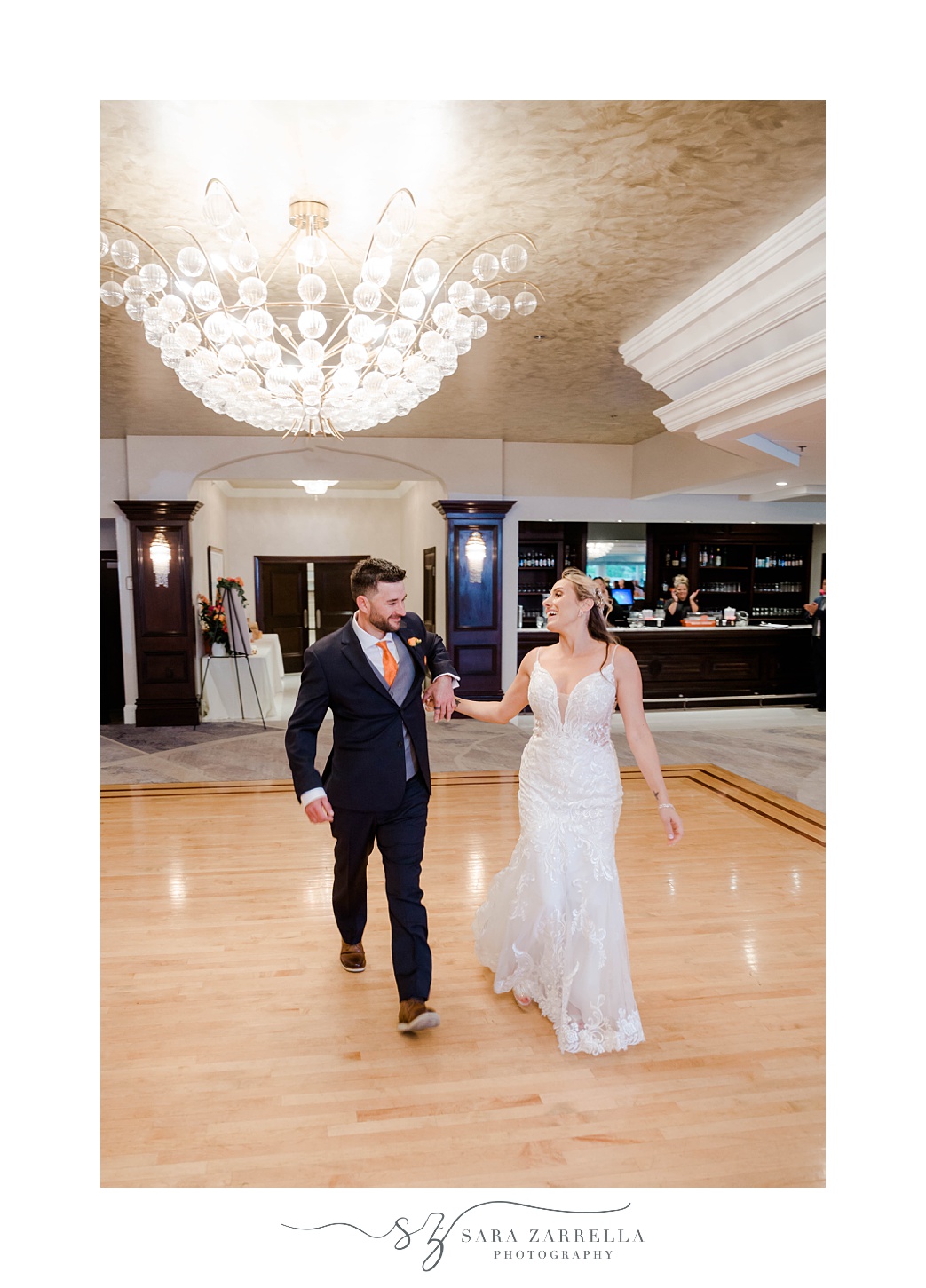 bride and groom hold hands walking across dance floor