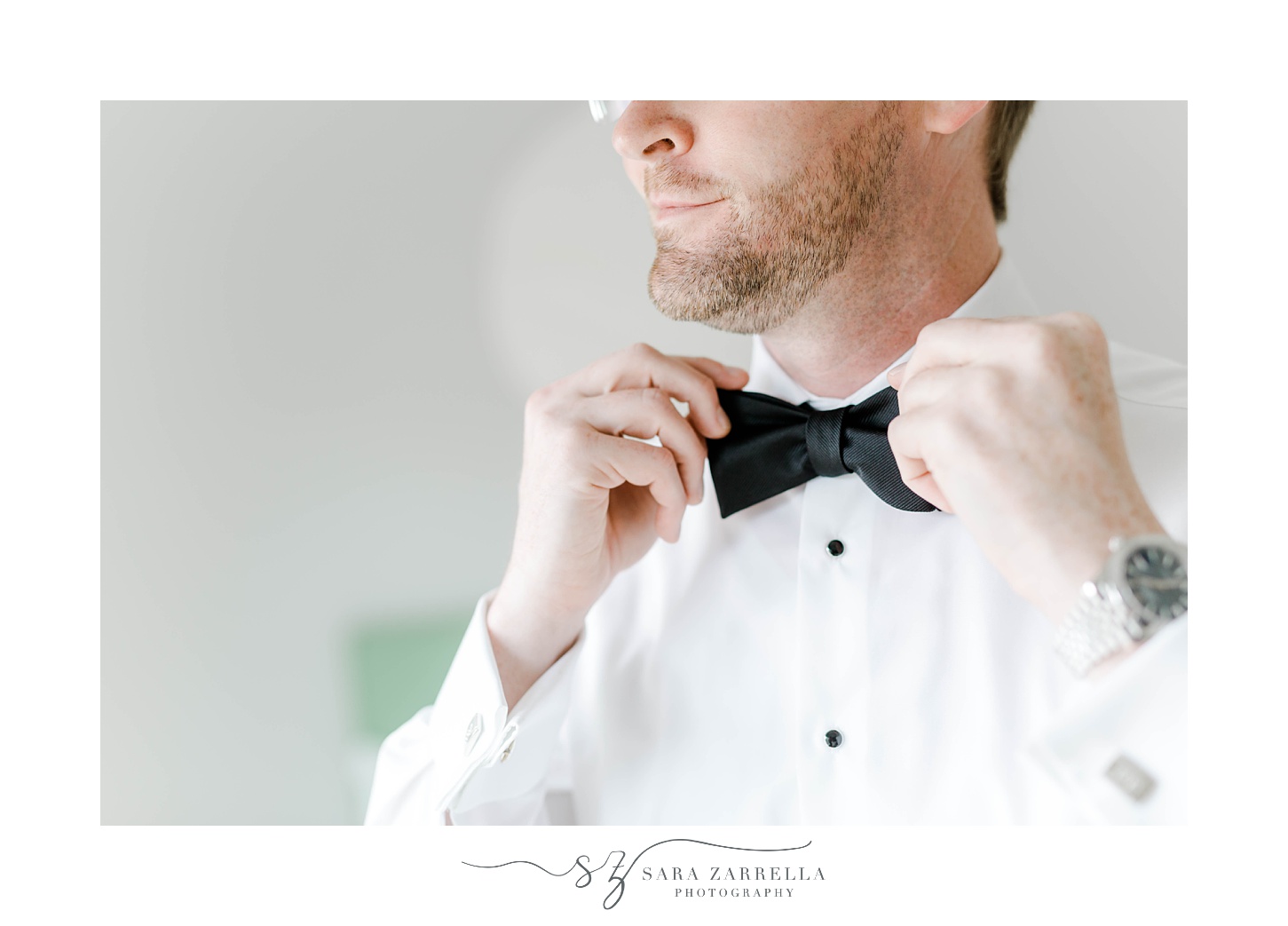 groom adjusts black bow tie for Rosecliff Mansion wedding
