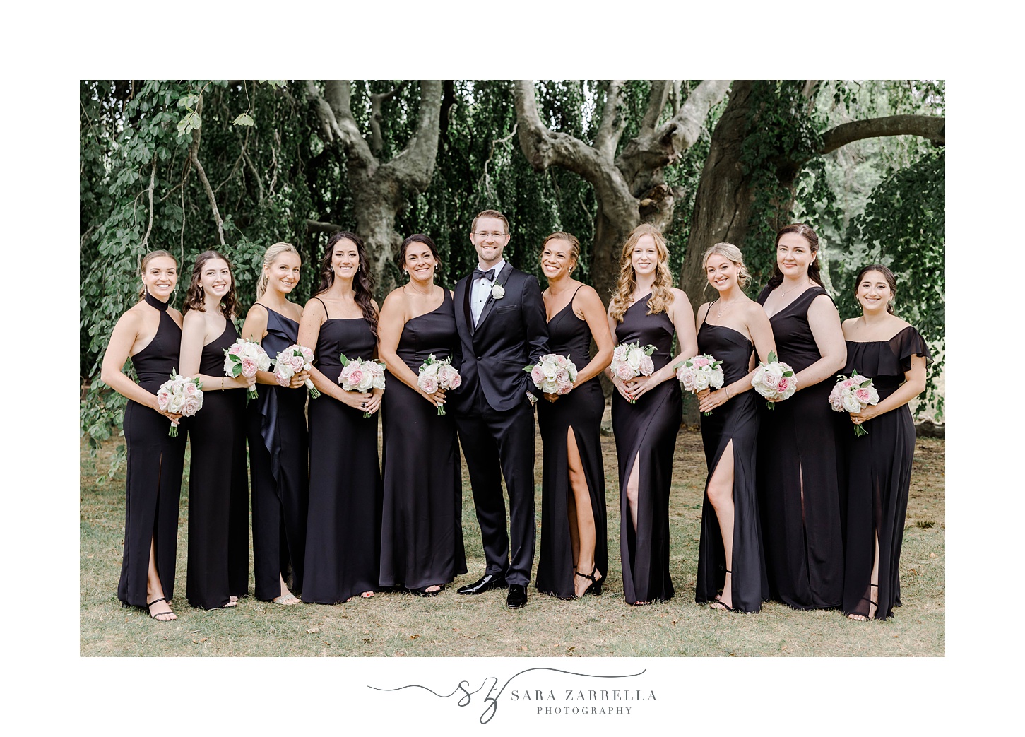 groom stands with bridesmaids in black gowns at The Elms