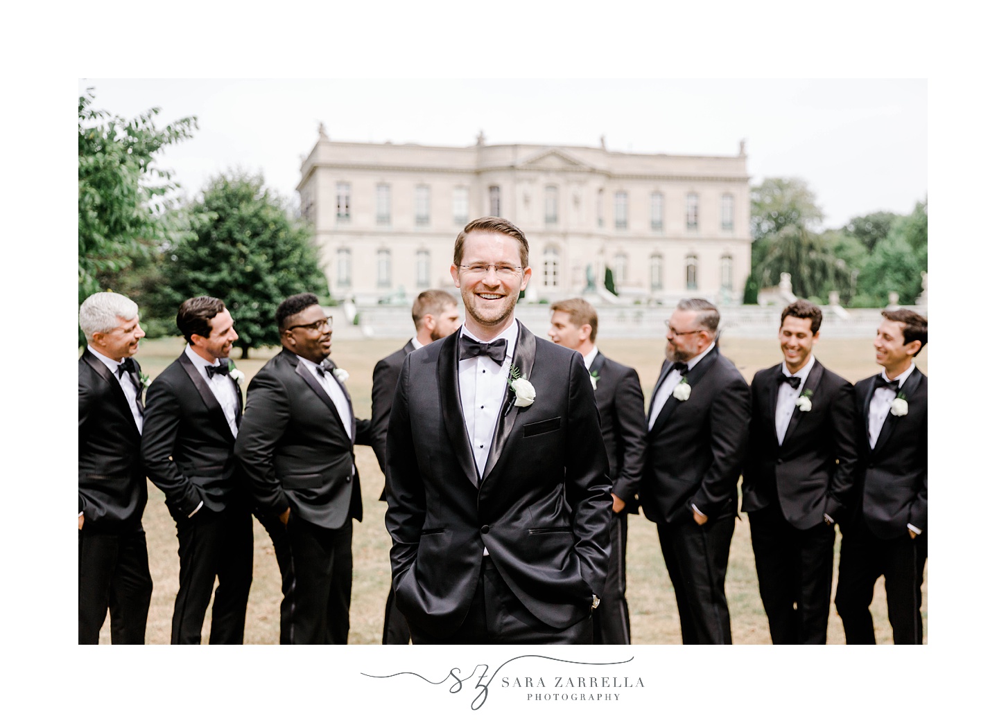 groom stands in front of groomsmen in black suits at The Elms
