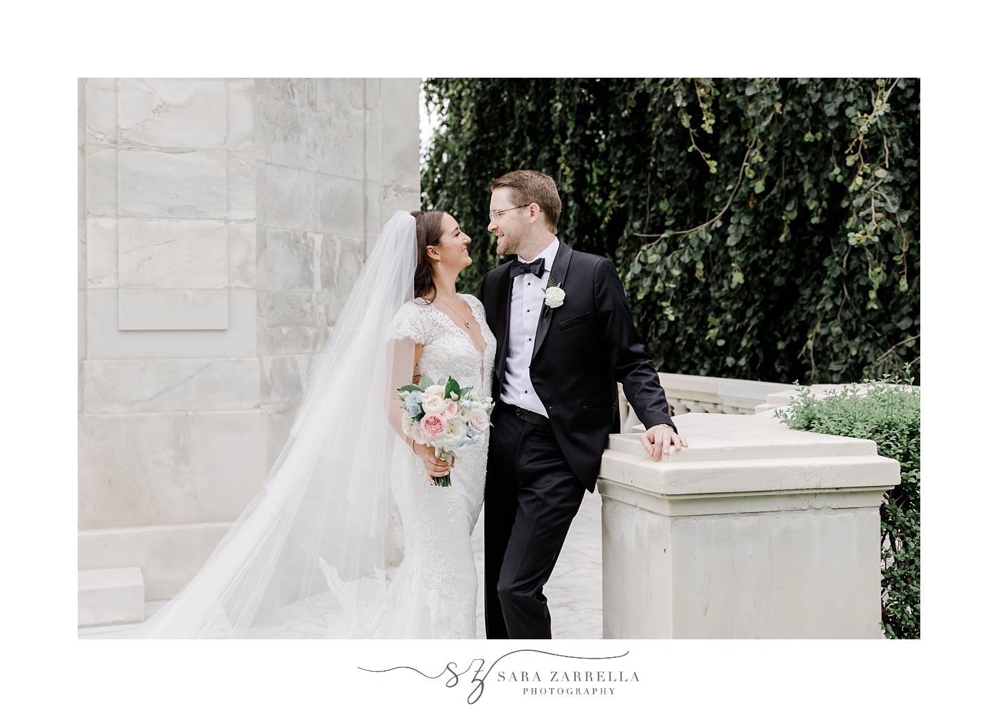 newlyweds smile together during portraits against marble walls at The Elms