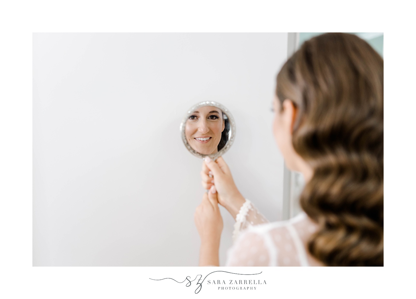 bride holds up classic silver mirror to look at makeup