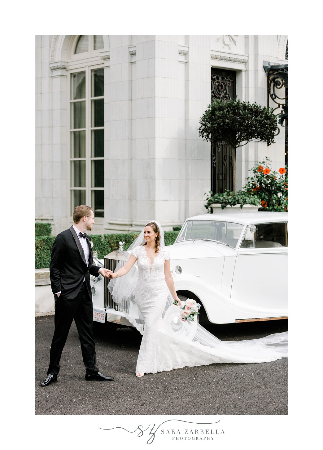 groom leads bride away from classic car at Rosecliff Mansion