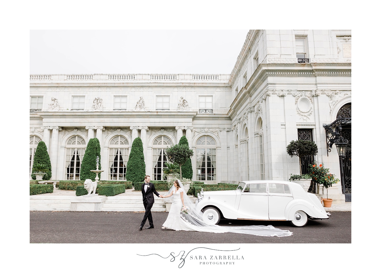 bride and groom walk by classic white car outside the entrance of Rosecliff Mansion