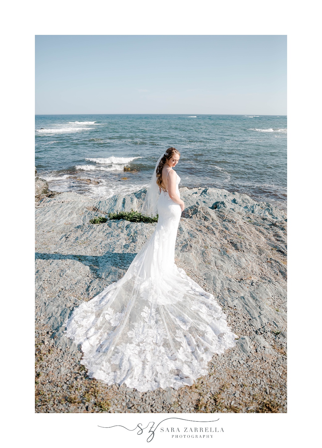 bride stands on rocks near Newport waterfront 