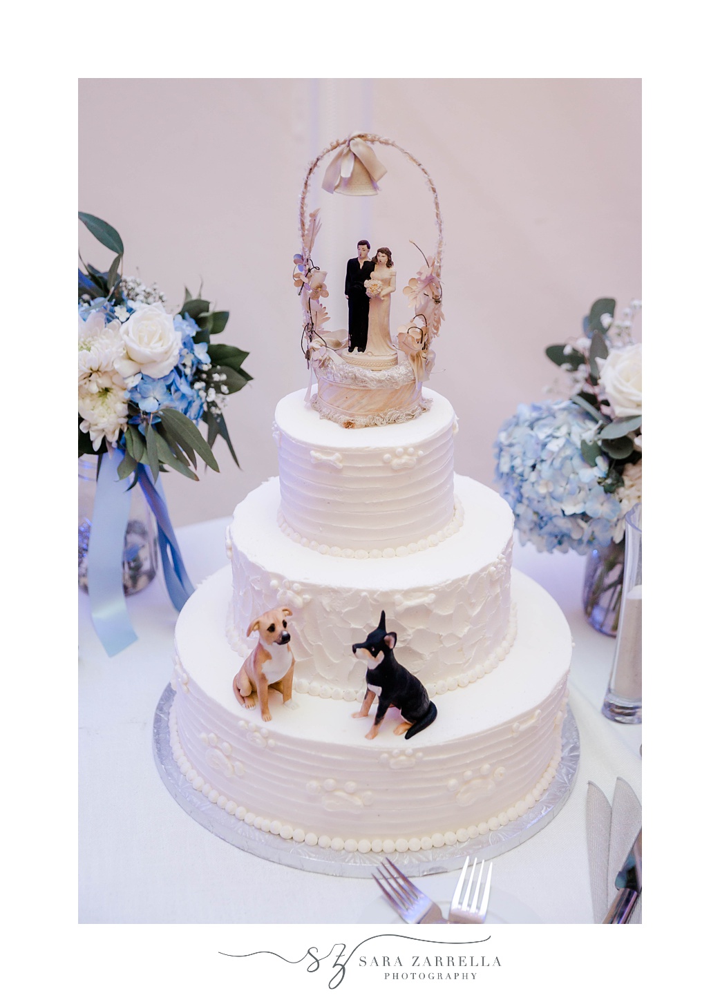 tiered wedding cake with couple topper and two dogs