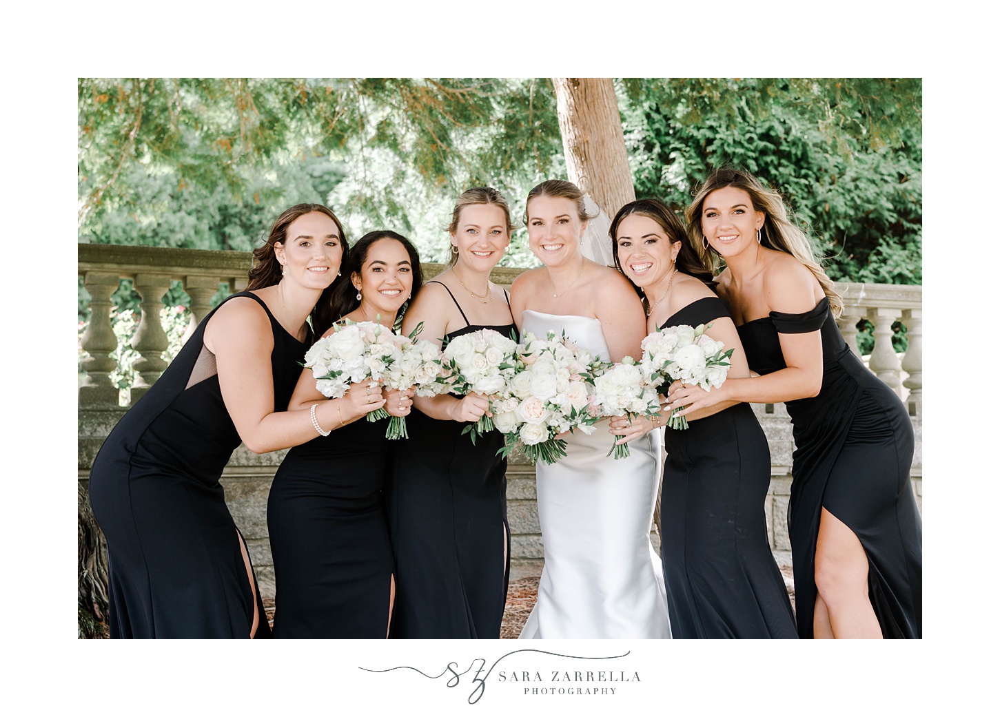 bride hugs together with bridesmaids in black gowns