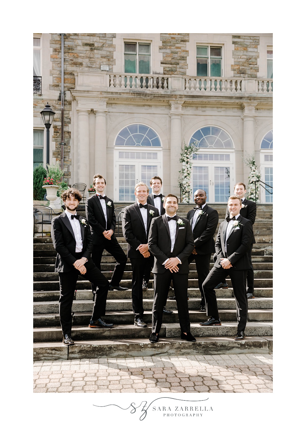 groom and groomsmen in classic tuxes stand on staircase at Aldrich Mansion