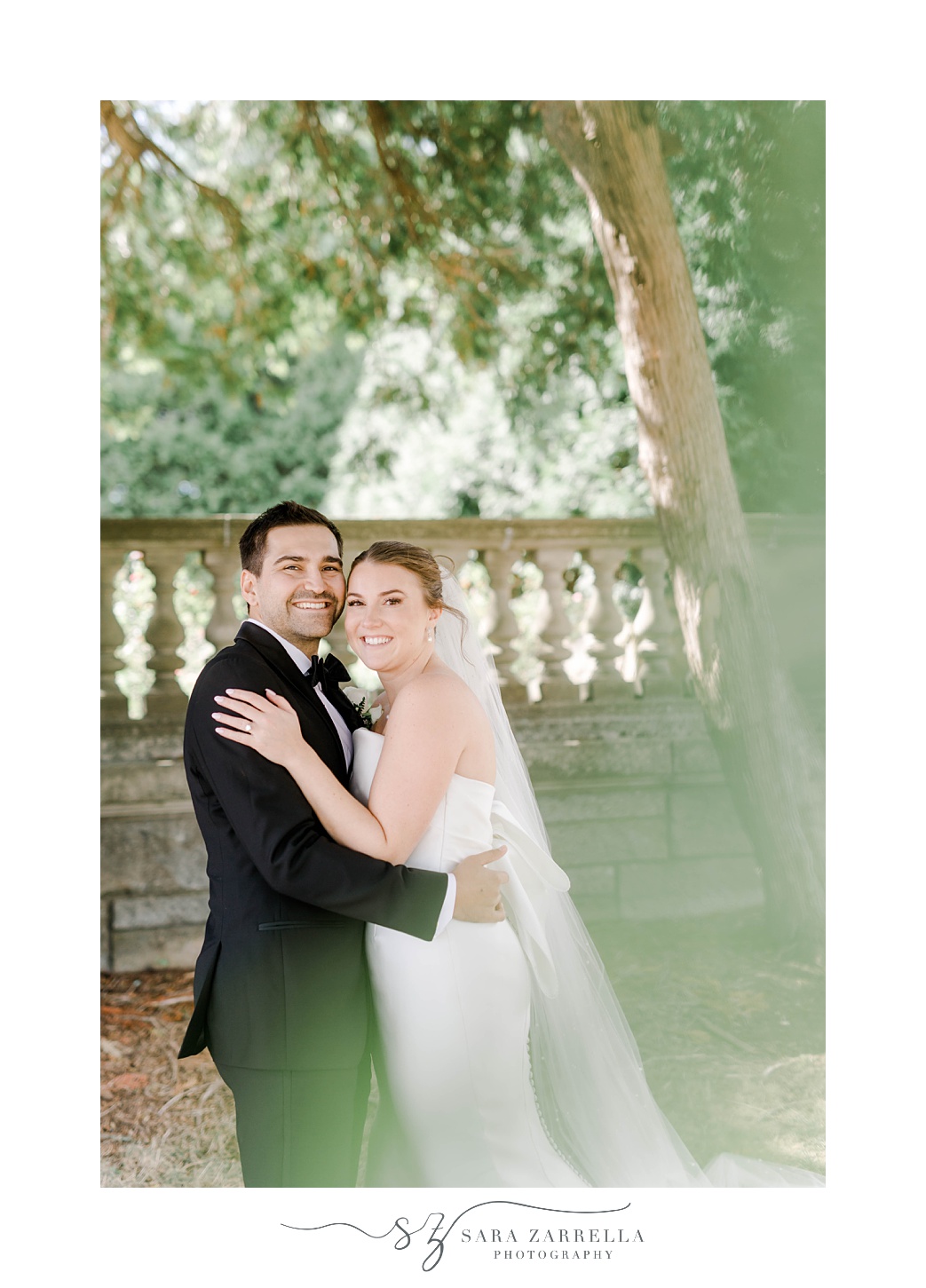 bride and groom hug leaning heads together along stone wall at Aldrich Mansion