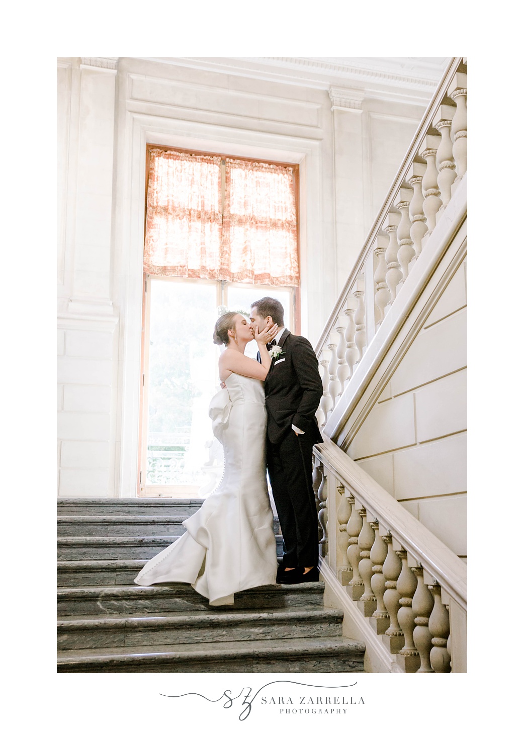newlyweds kiss on staircase in Rhode Island mansion
