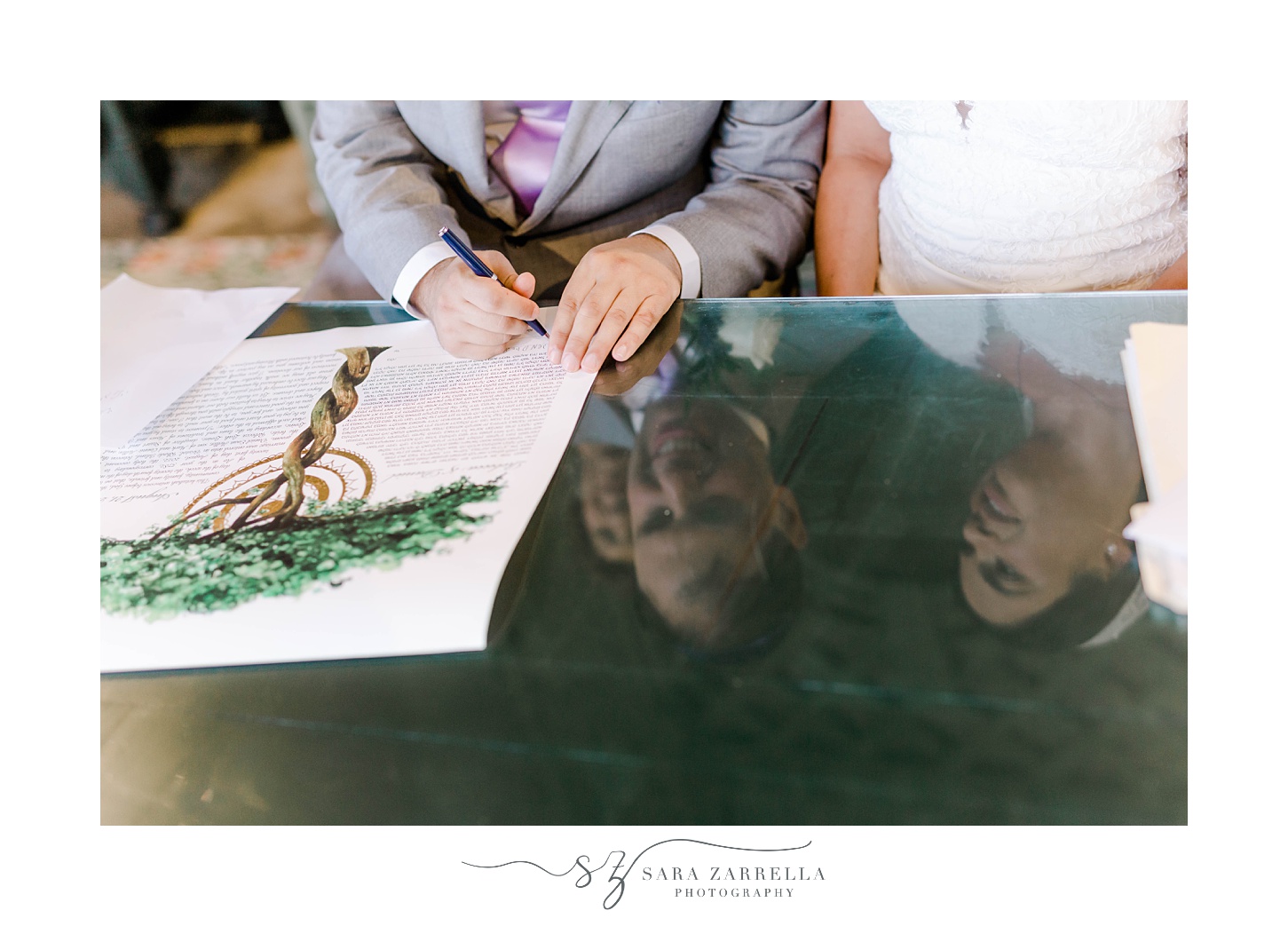 groom signs Ketubah with bride next to him