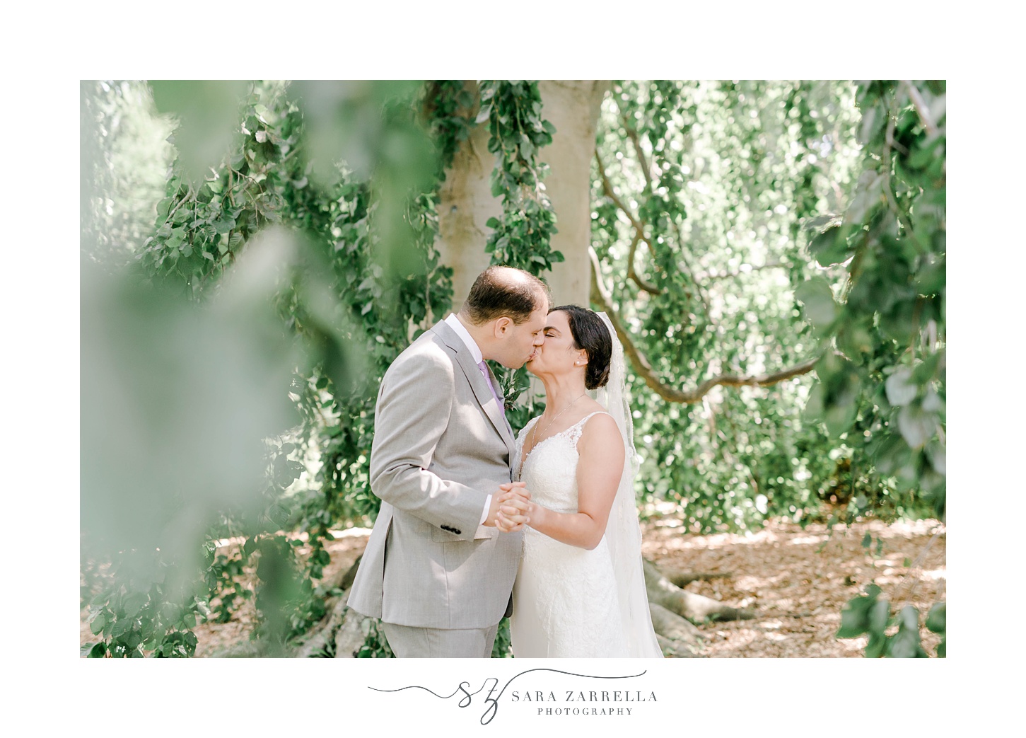 groom leans in to kiss bride during portraits under weeping willow tree