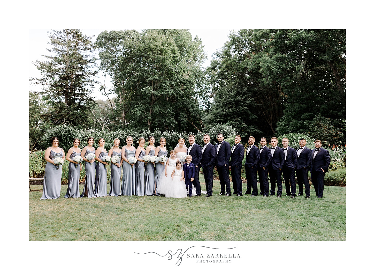 newlyweds pose with wedding party in blue dresses and navy suits