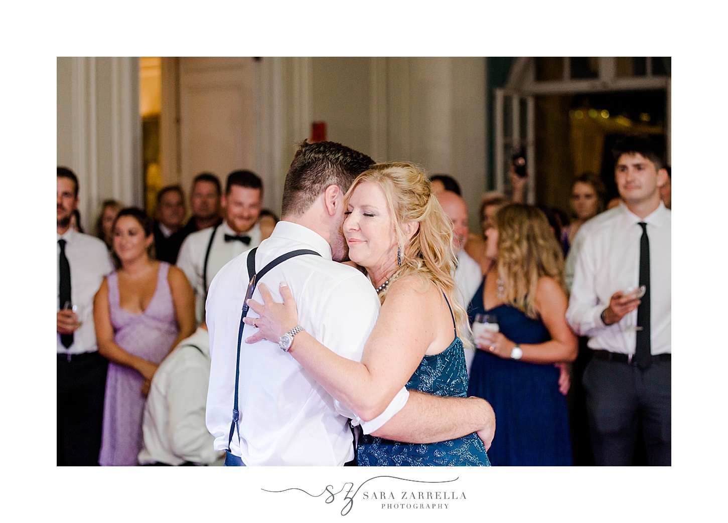 groom in suspenders hugs mom during dance