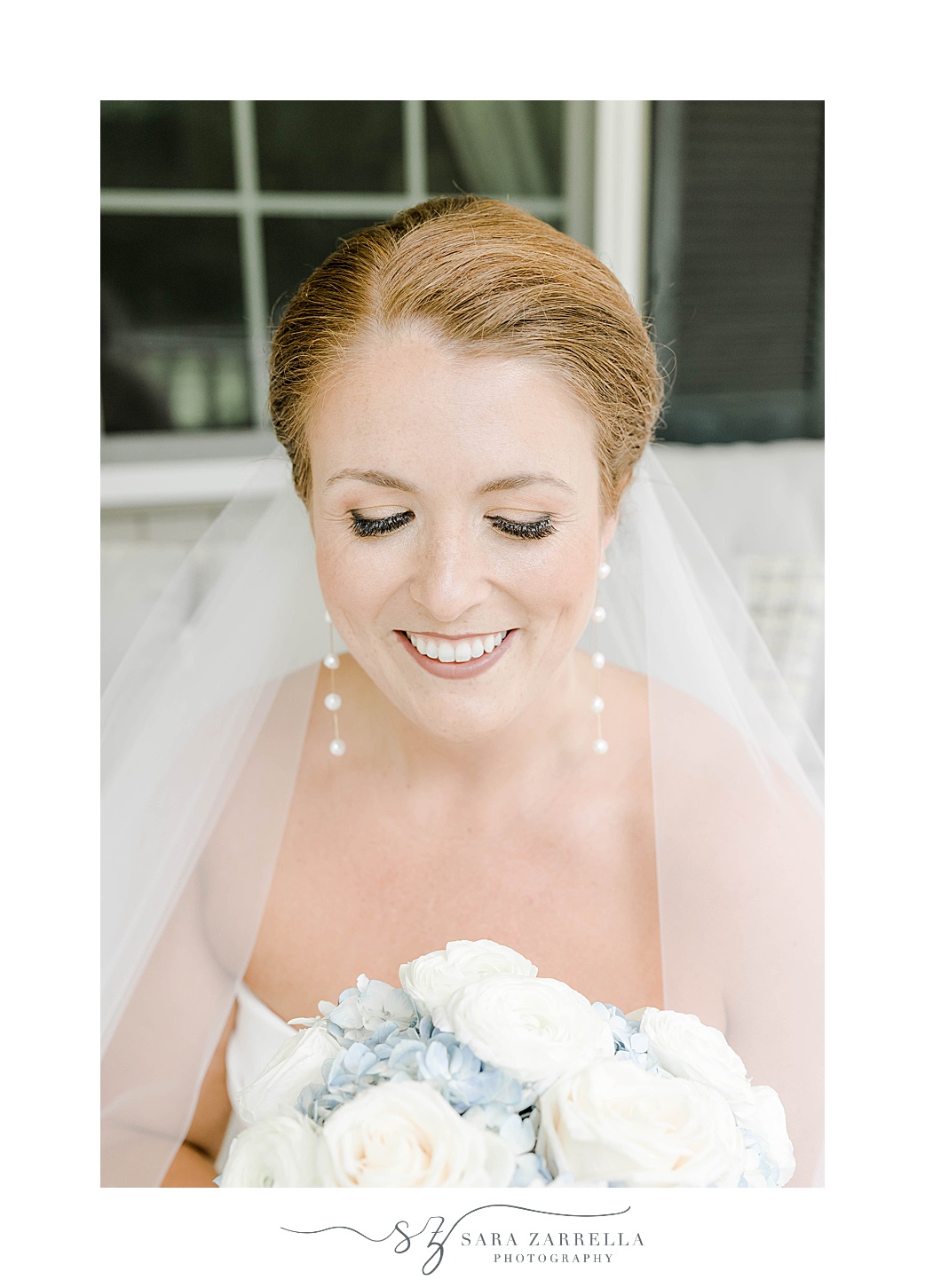 bride looks down at bouquet of white and blue flowers