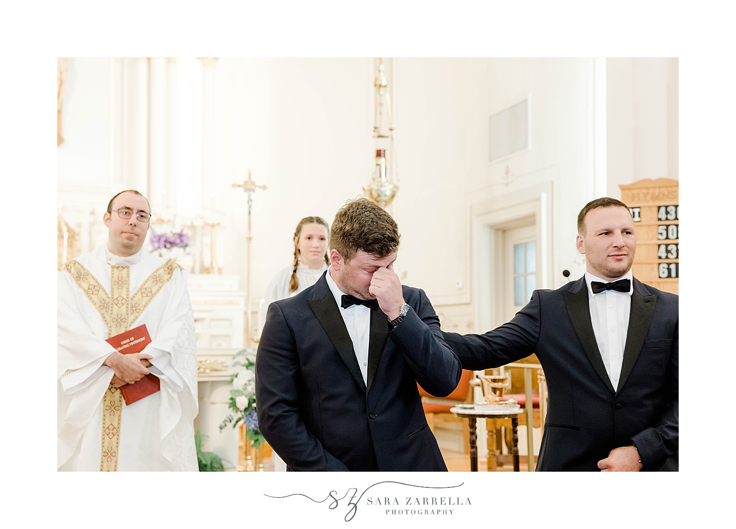 best man taps groom's shoulder while he cries watching bride