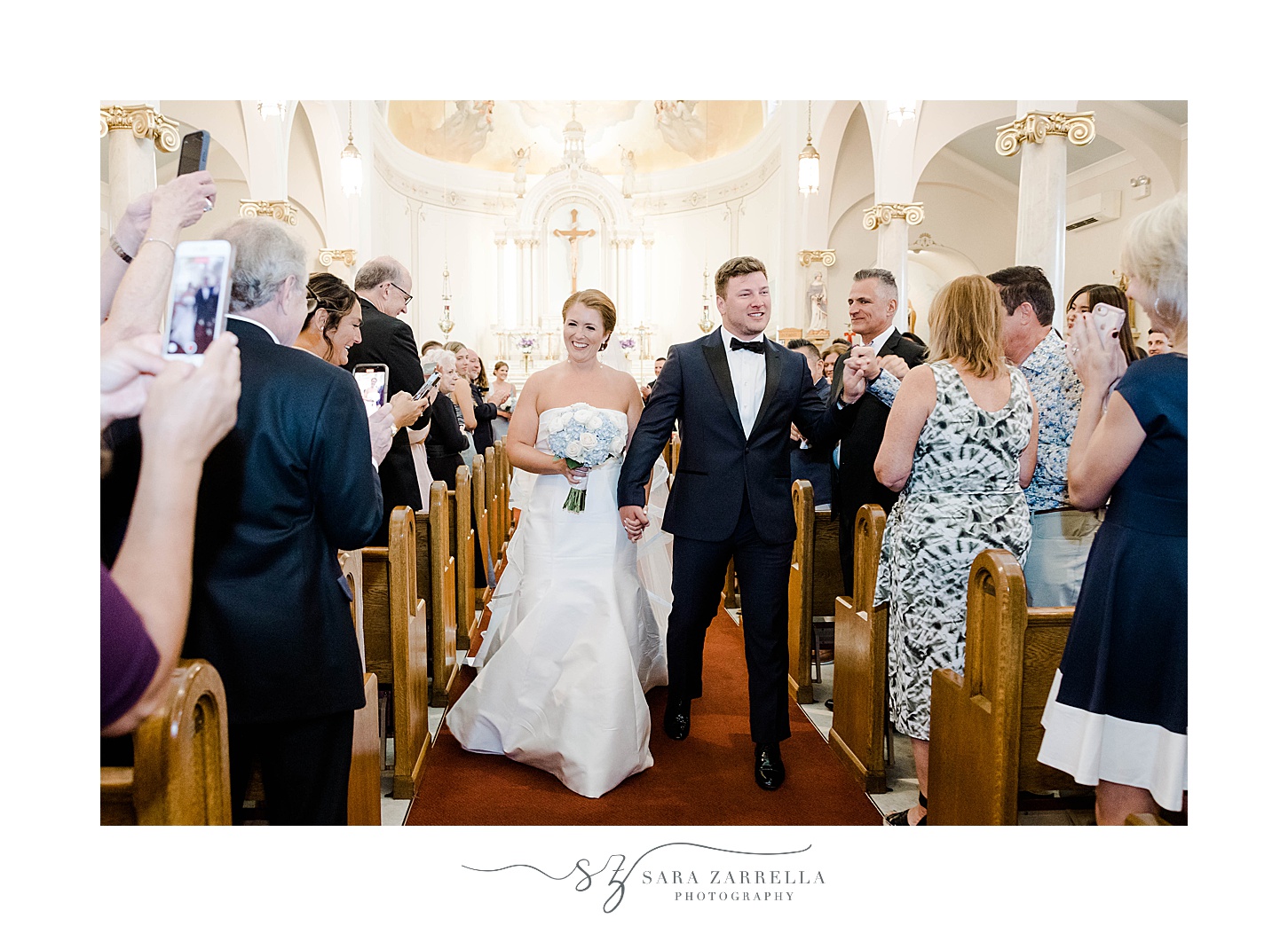 bride and groom walk up aisle after traditional church wedding in Rhode Island