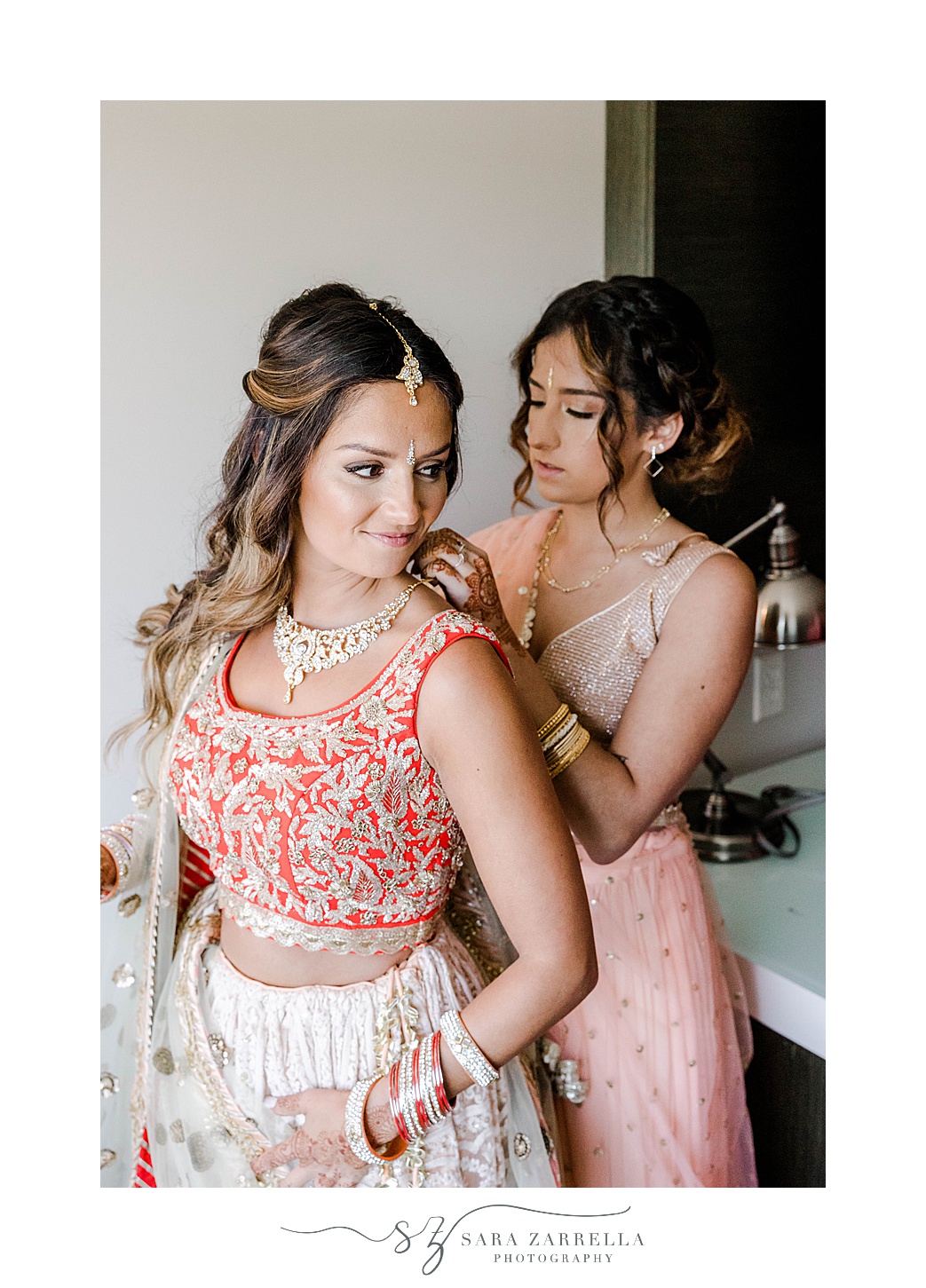 bridesmaid helps bride into sari for Indian wedding at Newport Beach House