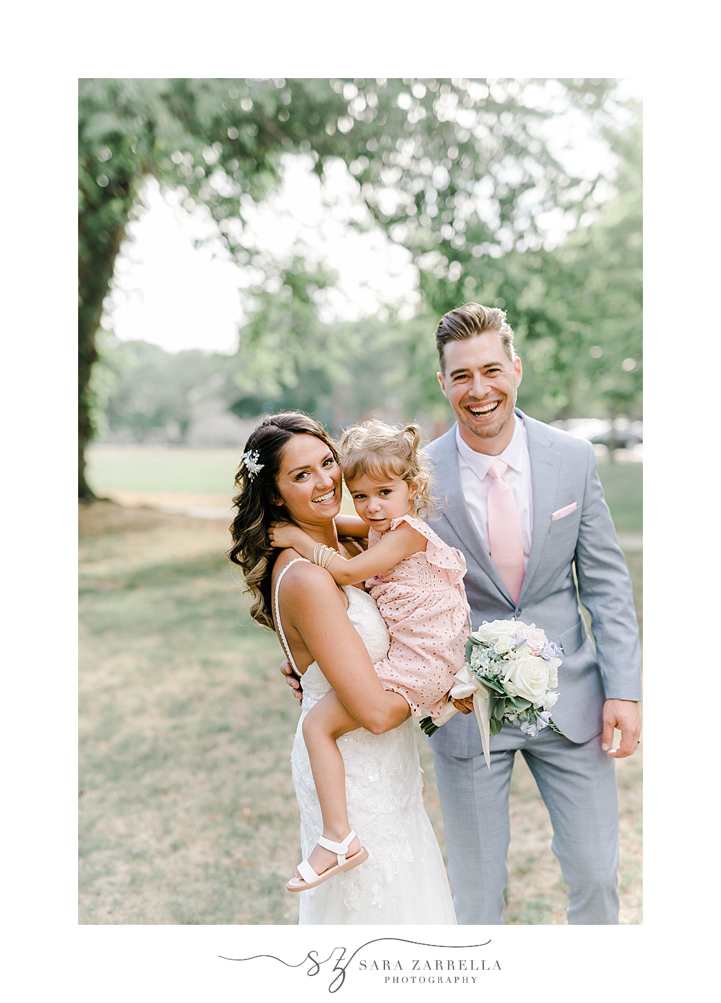 bride and groom pose with daughter in pink gown