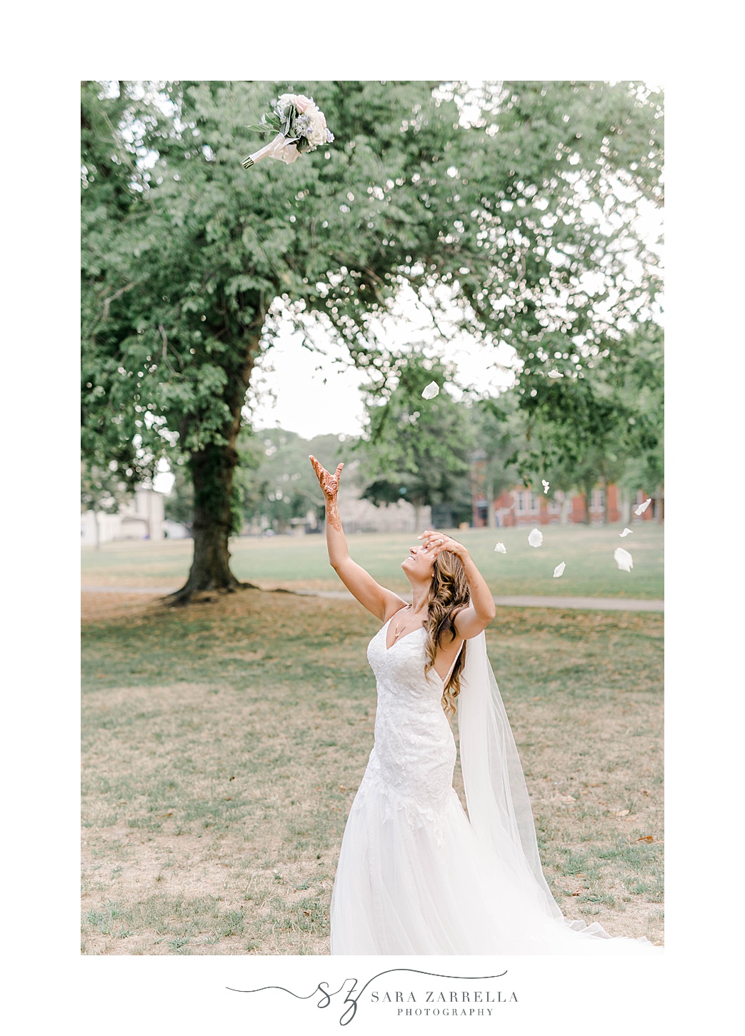 bride tosses bouquet in the air during Newport RI wedding portraits 